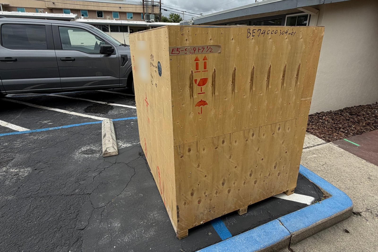 A tall plywood shipping crate standing in a parking space outside the UNDR lab in Redding, California